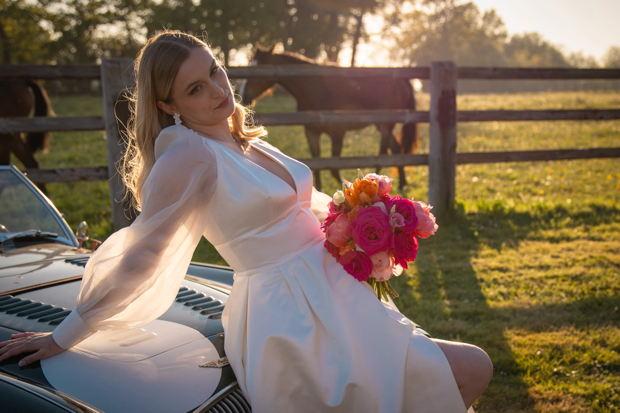 La mariée prend place dans une voiture ancienne, son bouquet à la main