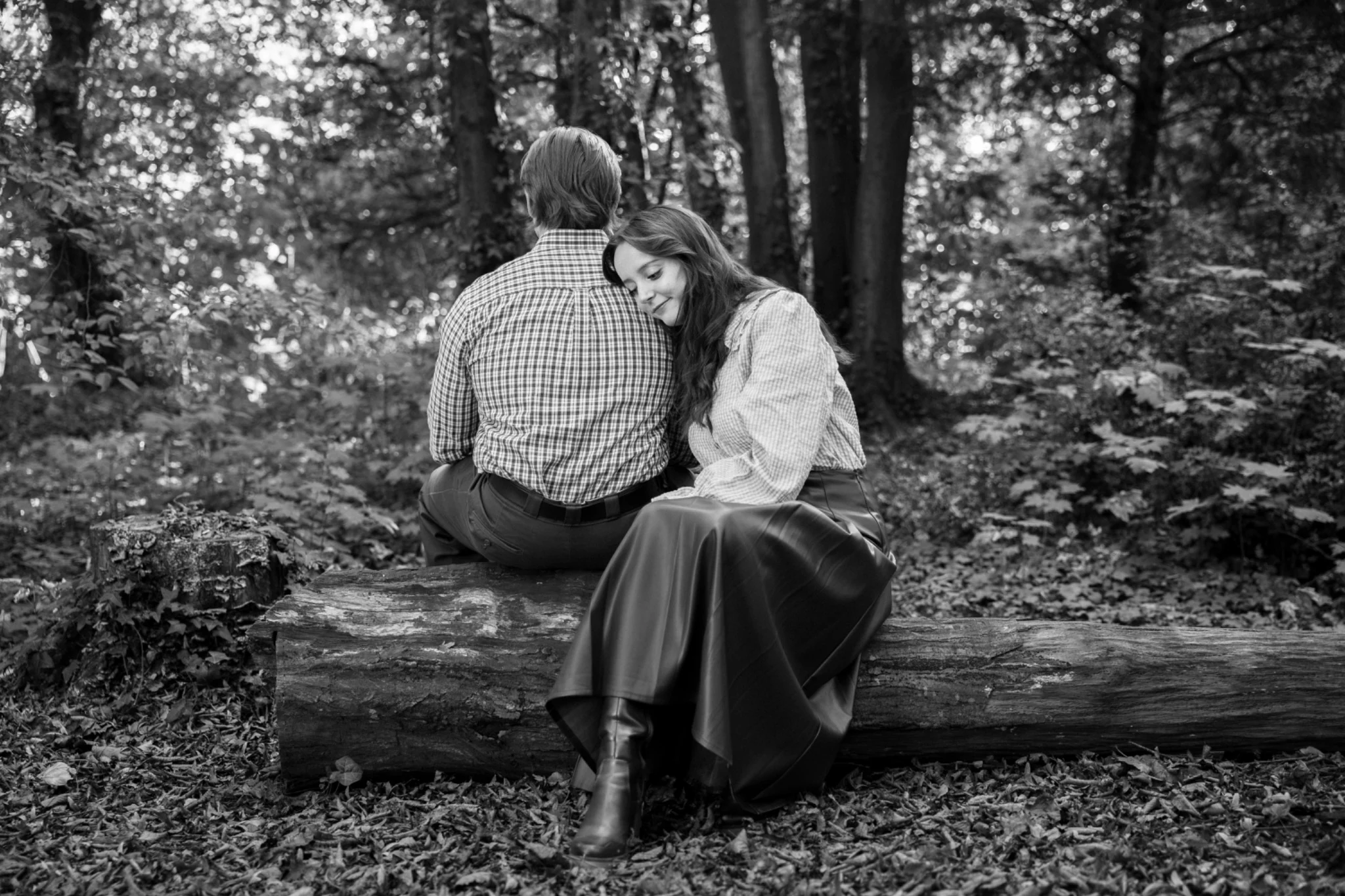 Un couple partage un instant tendre, assis sur un banc en forêt