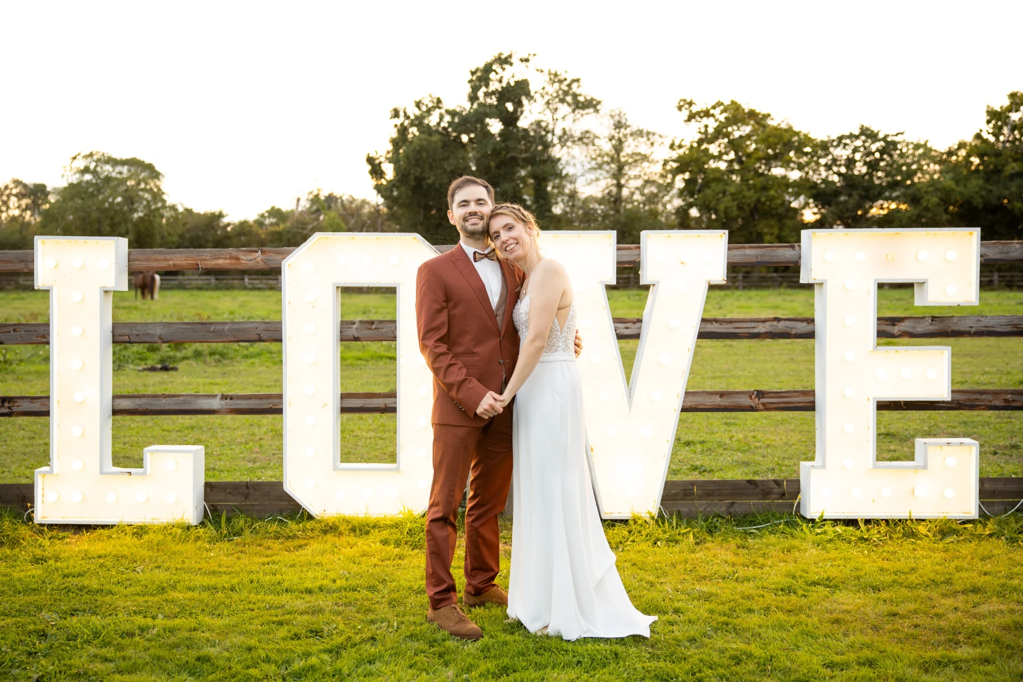 Les mariés posent devant de grandes lettres LOVE dans le jardin