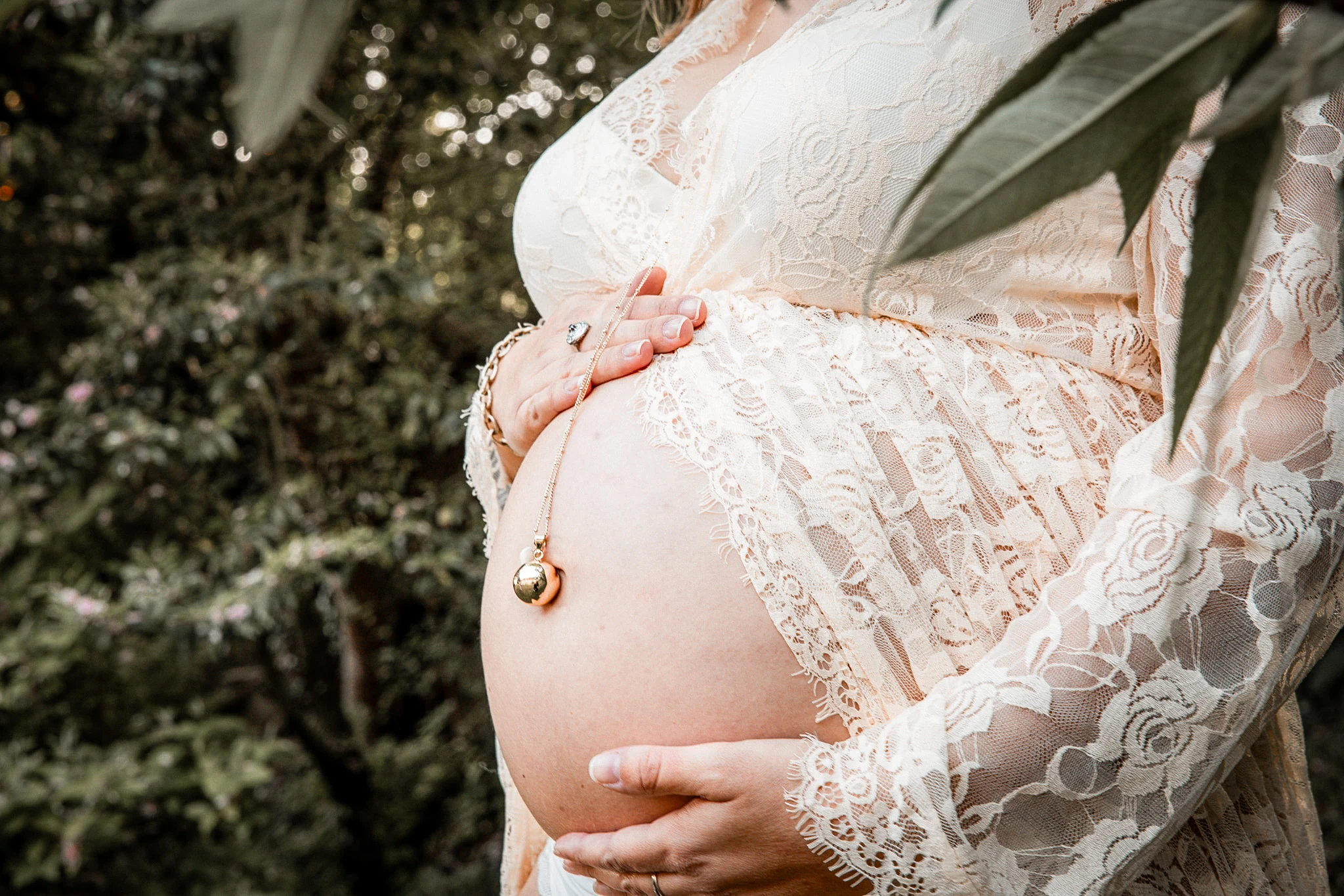 Une future maman pose les mains sur son ventre pendant une séance photo de grossesse